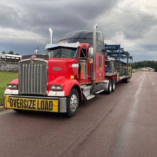 Red Kenworth W900 with oversize-load car-hauler trailer, ready to roll
